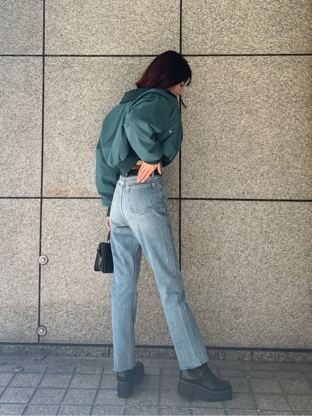 ブラック系のハンドバッグ、ブルー系のデニムパンツ、ブルー系のMA-1を着用したレディースの秋コーディネートの3枚目の写真