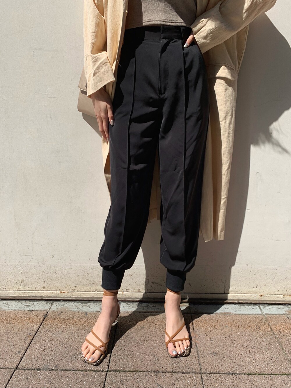 ベージュ系のチェスターコート、ブラック系のその他パンツ、ブラウン系のサンダルを着用したレディースの春コーディネートの5枚目の写真