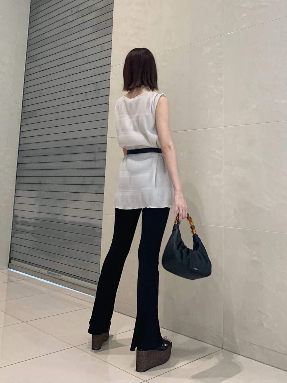 ホワイト系のTシャツ/カットソー、ブラック系のその他パンツ、ブラック系のハンドバッグを着用したレディースの春コーディネートの2枚目の写真