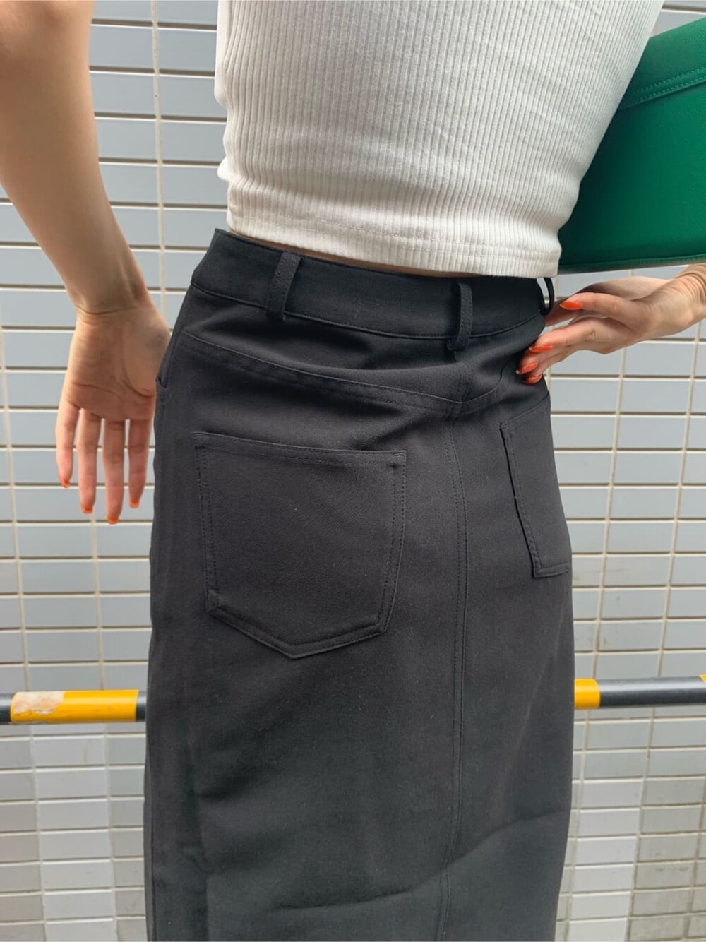 ブラック系のスカート、ブラック系のブーツ、グリーン系のショルダーバッグを着用したレディースの夏コーディネートの7枚目の写真