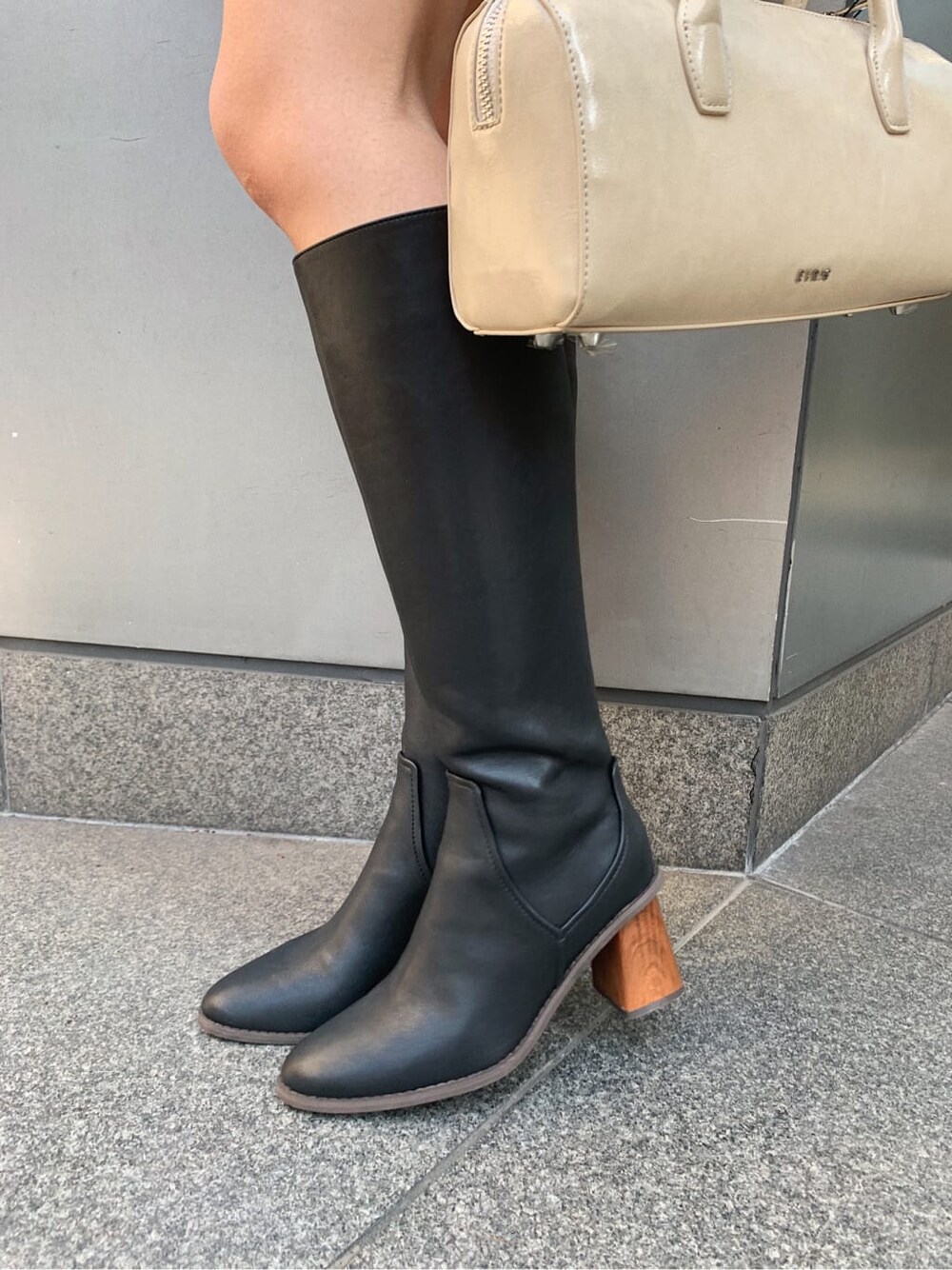 ブラック系のブーツ、ベージュ系のボストンバッグ、ホワイト系のシャツ/ブラウスを着用したレディースの冬コーディネートの8枚目の写真