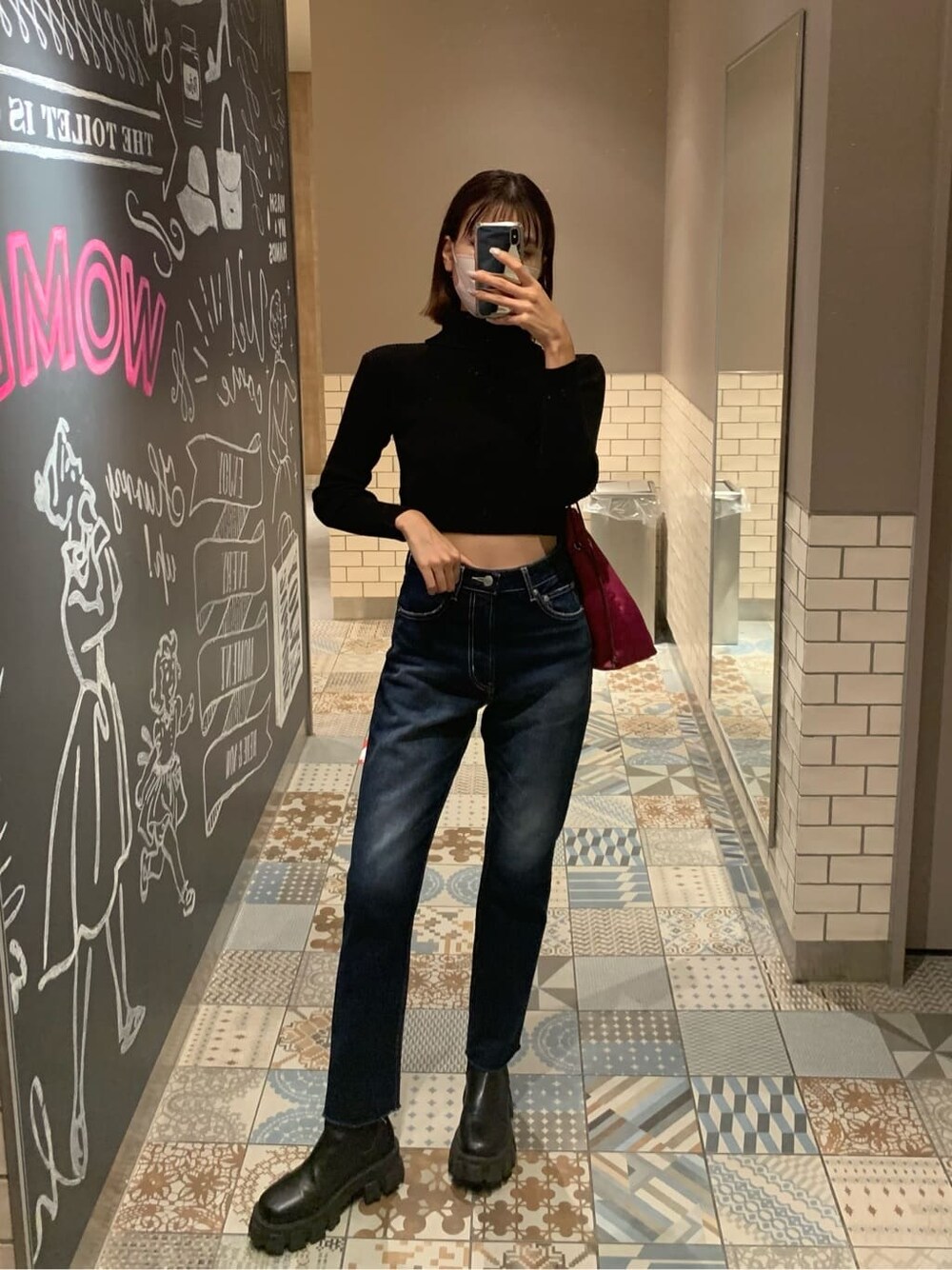 ブラック系のニット/セーター、ピンク系のハンドバッグ、ブルー系のデニムパンツを着用したレディースの秋コーディネートの2枚目の写真