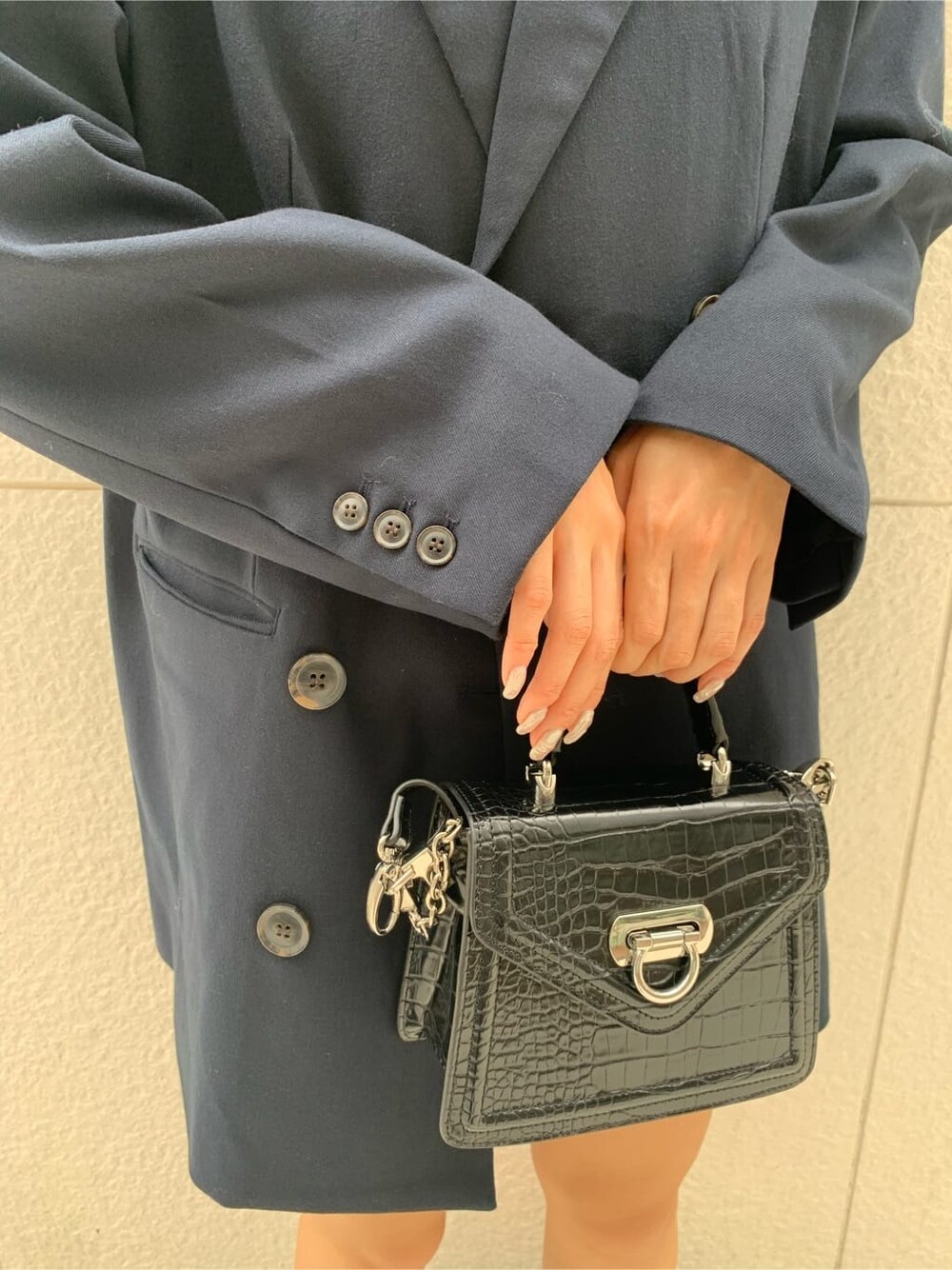 ブルー系のテーラードジャケット、ブラック系のハンドバッグ、ブラック系のブーツを着用したレディースの秋コーディネートの9枚目の写真