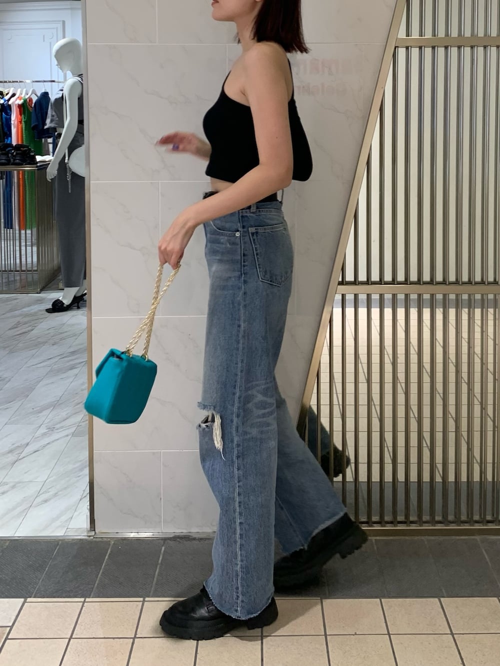 ブラック系のブーツ、ブルー系のデニムパンツ、ブルー系のショルダーバッグを着用したレディースの夏コーディネートの3枚目の写真