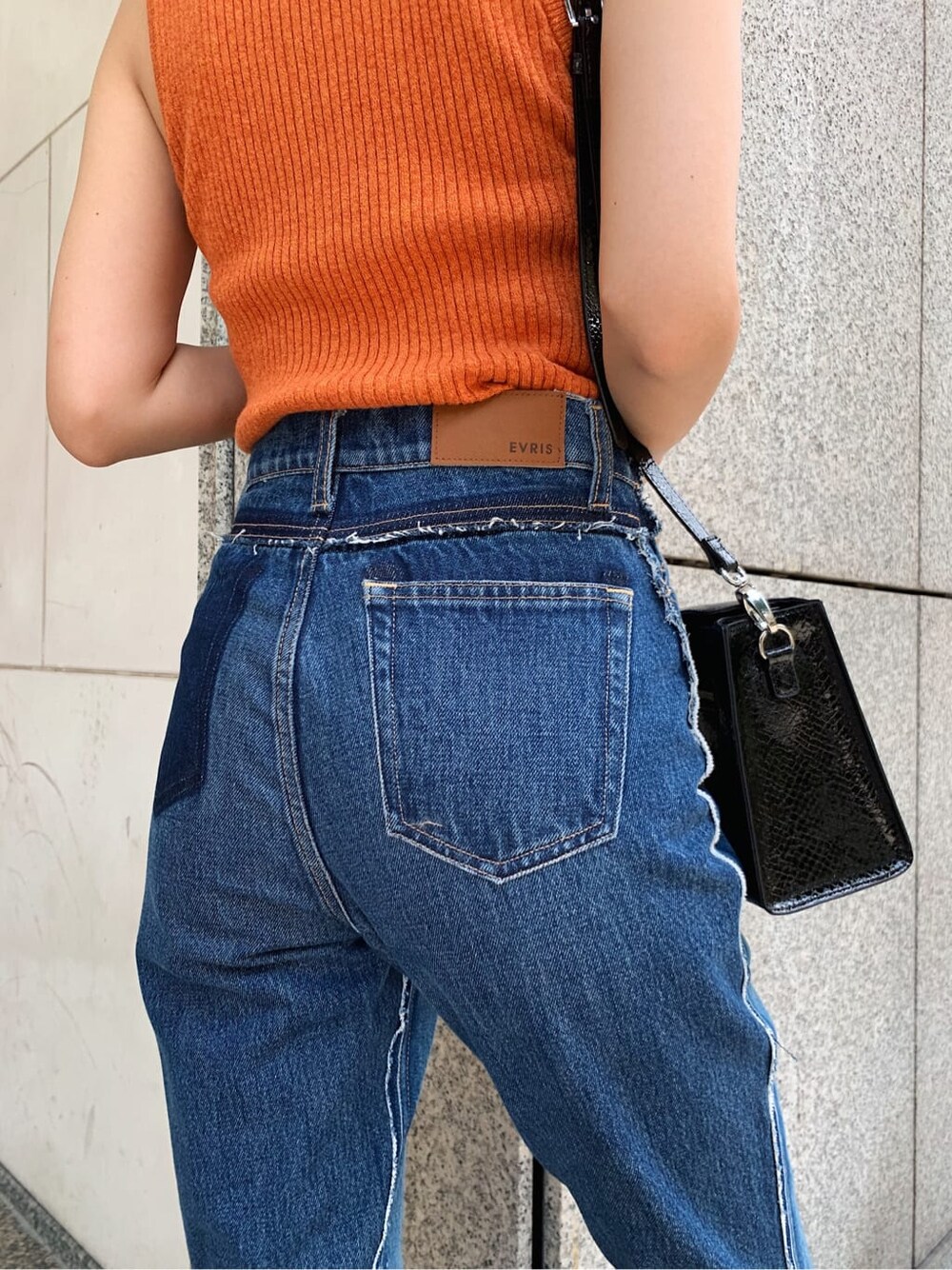 ブルー系のデニムパンツ、ブラック系のサンダル、オレンジ系のニット/セーターを着用したレディースの夏コーディネートの6枚目の写真