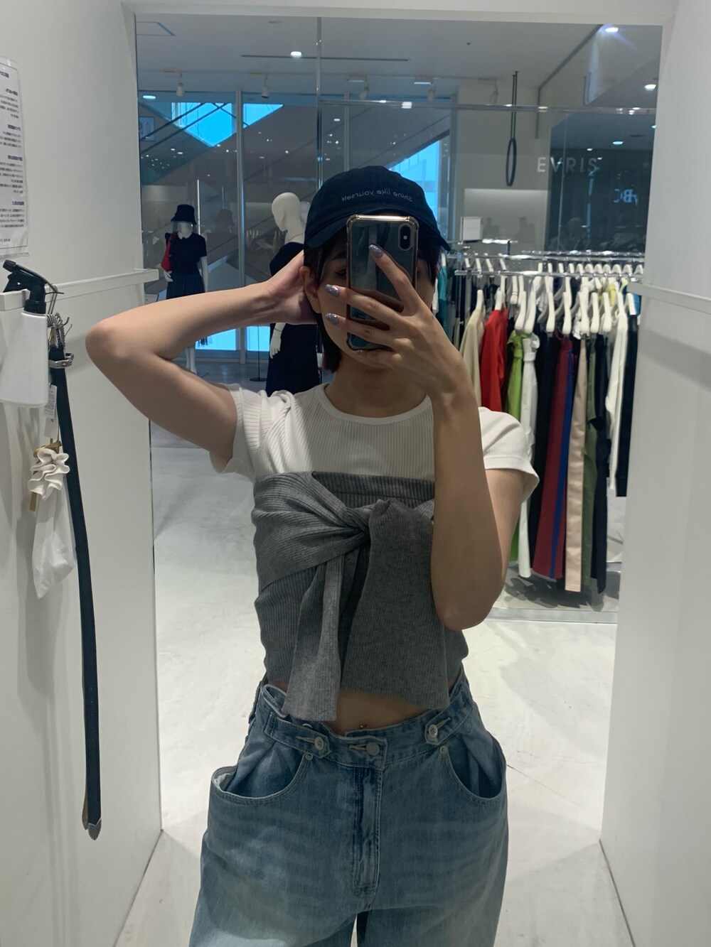 ブルー系のデニムパンツ、ブラック系のブーツ、グレー系のチューブトップを着用したレディースの春コーディネートの4枚目の写真