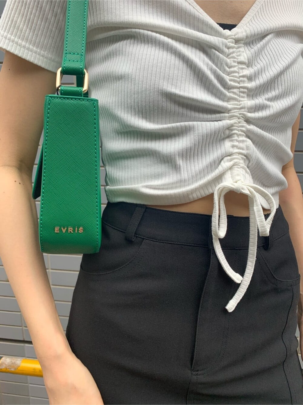 ブラック系のスカート、ブラック系のブーツ、グリーン系のショルダーバッグを着用したレディースの夏コーディネートの9枚目の写真