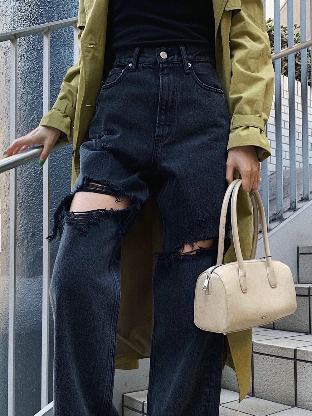 ブラック系のブーツ、ブラック系のデニムパンツ、ベージュ系のボストンバッグを着用したレディースの春コーディネートの6枚目の写真