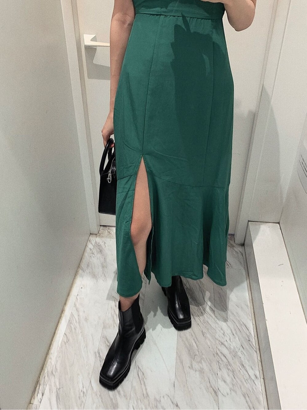 ブラック系のブーツ、ブラック系のショルダーバッグ、グリーン系のワンピースを着用したレディースの春コーディネートの5枚目の写真