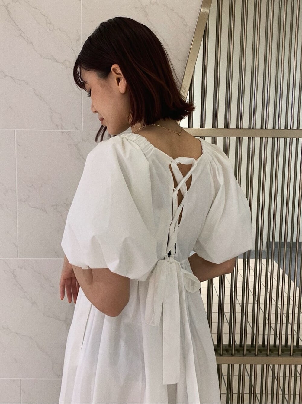 ホワイト系のワンピース、ブラック系のショルダーバッグ、その他のサンダルを着用したレディースの春コーディネートの4枚目の写真