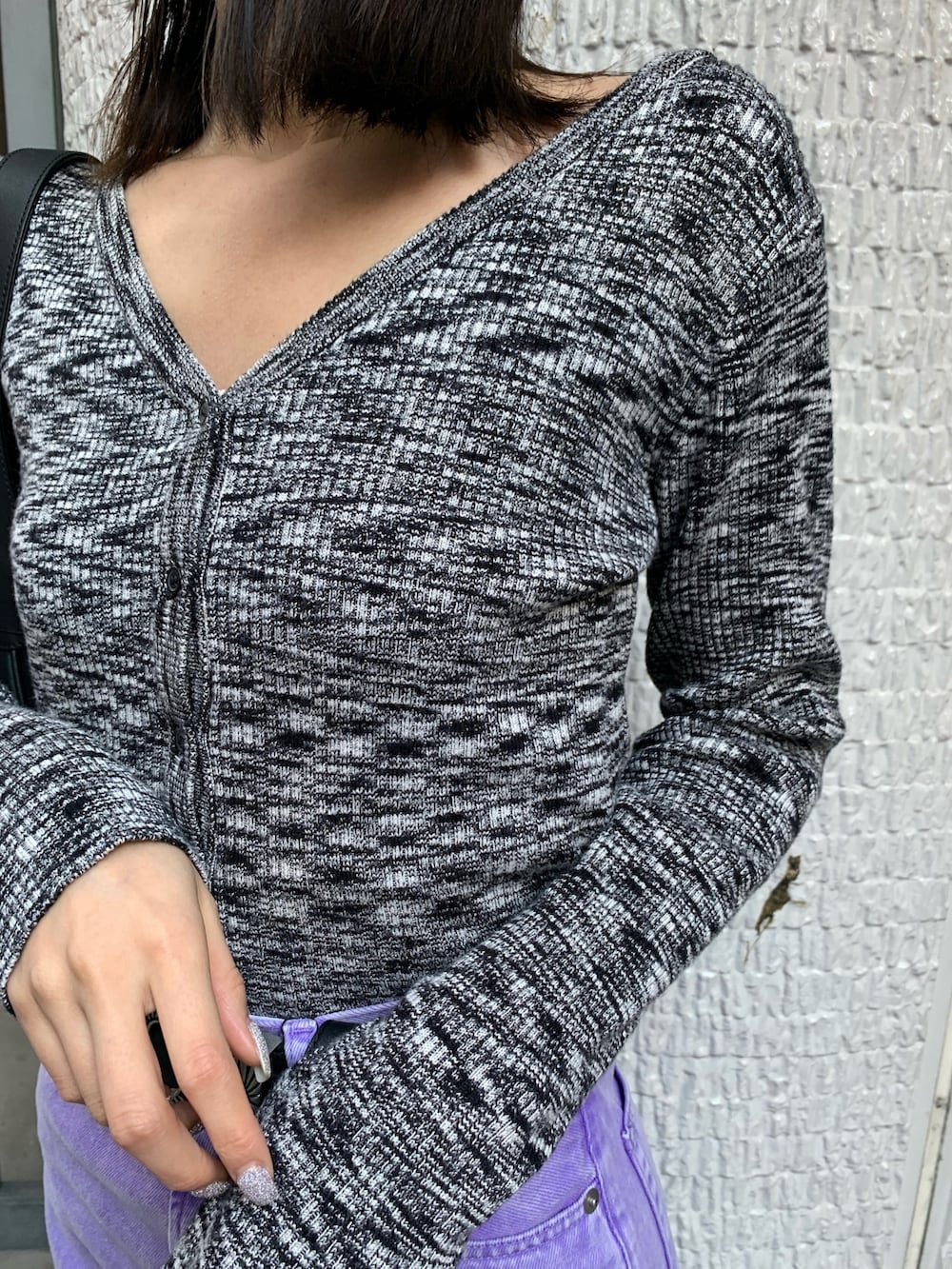 パープル系のデニムパンツ、ブラック系のニット/セーター、ブラック系のハンドバッグを着用したレディースの冬コーディネートの5枚目の写真