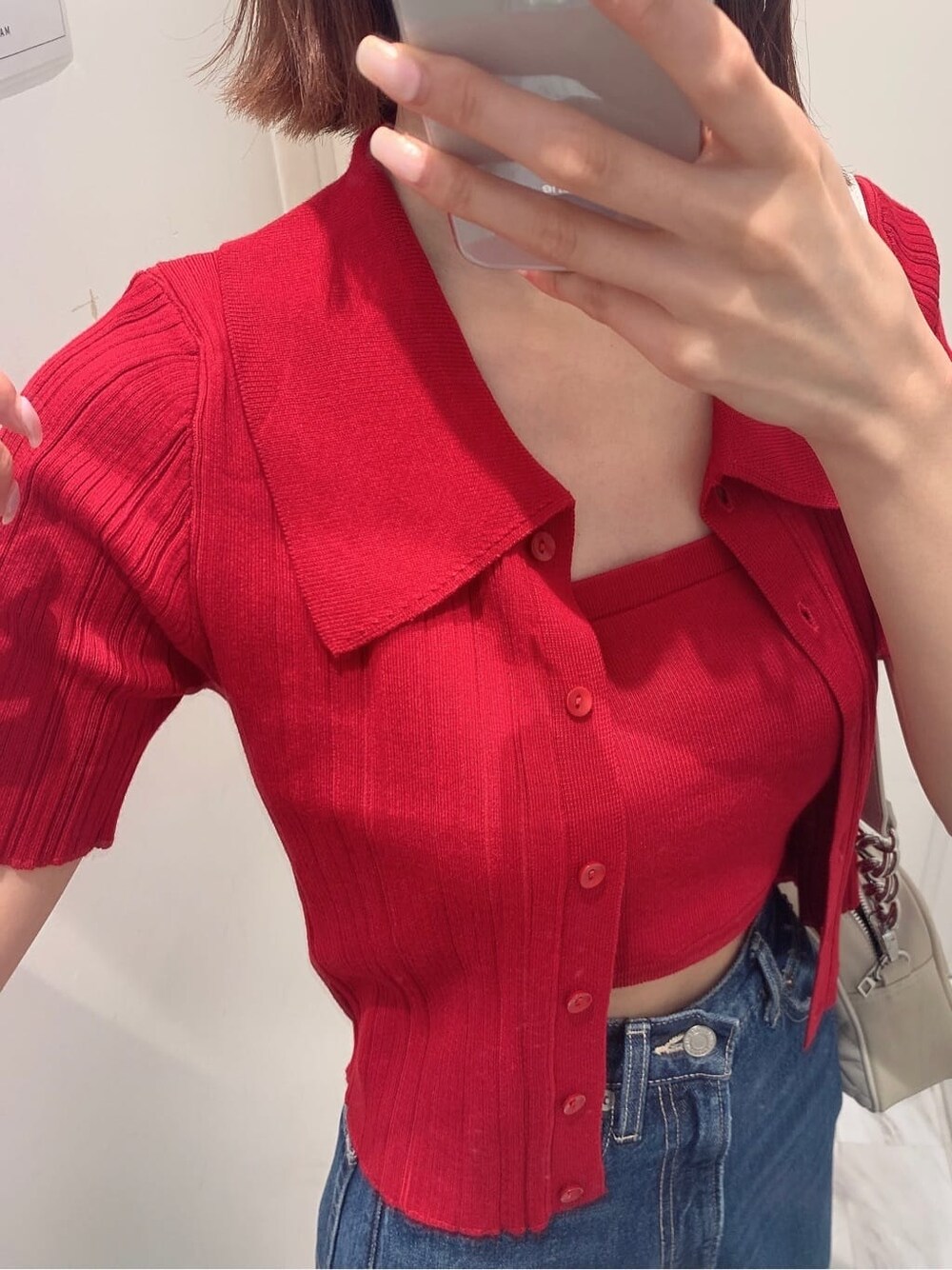 ブルー系のデニムパンツ、ホワイト系のショルダーバッグ、レッド系のニット/セーターを着用したレディースの夏コーディネートの4枚目の写真