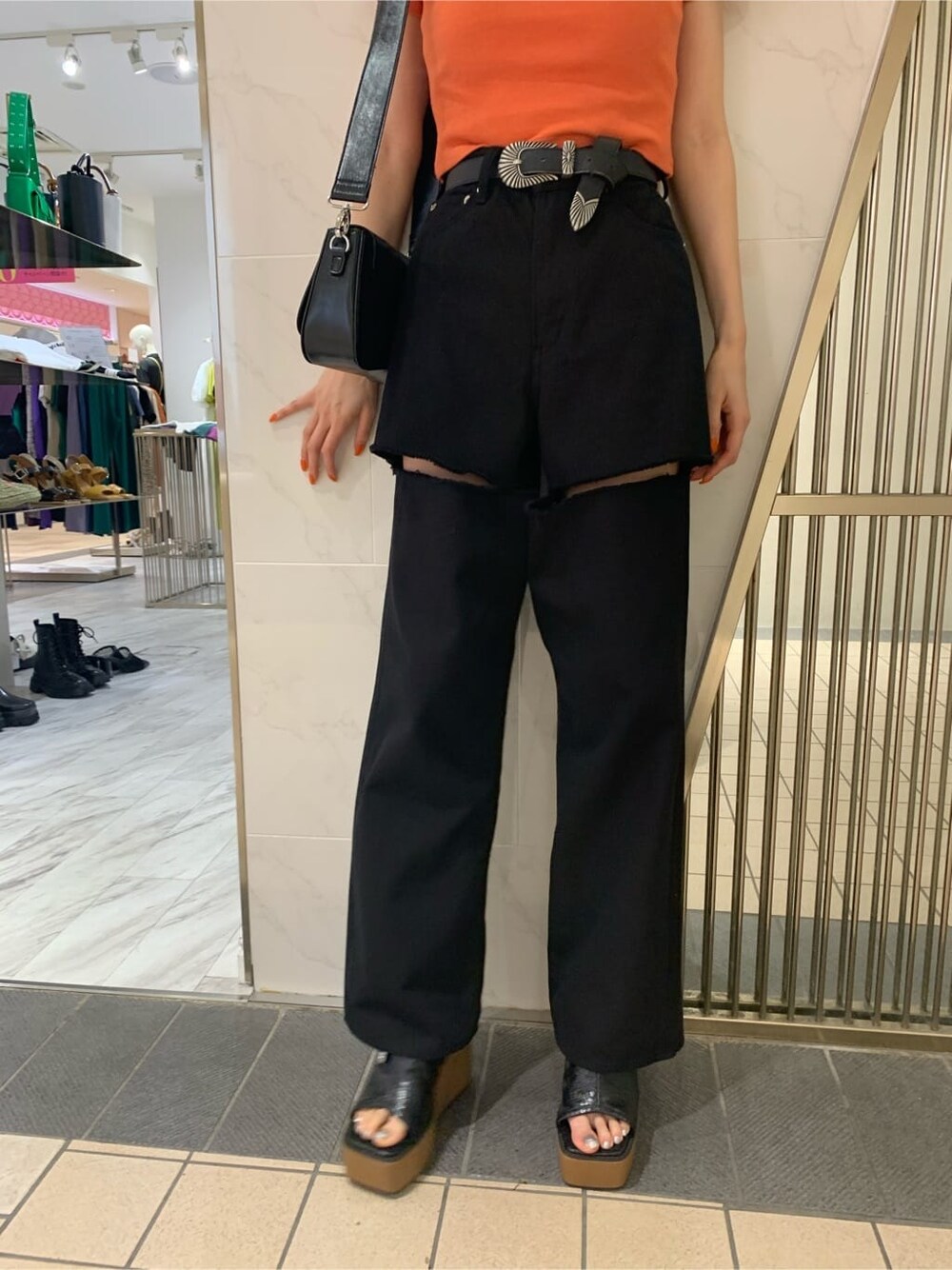 オレンジ系のTシャツ/カットソー、ブラック系のサンダル、ブラック系のショルダーバッグを着用したレディースの春コーディネートの5枚目の写真