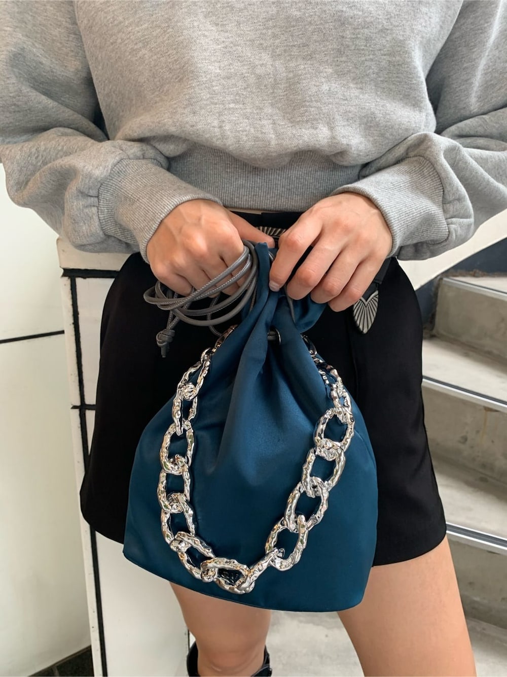 ブラック系のブーツ、ブルー系のハンドバッグ、グレー系のスウェットを着用したレディースの秋コーディネートの7枚目の写真