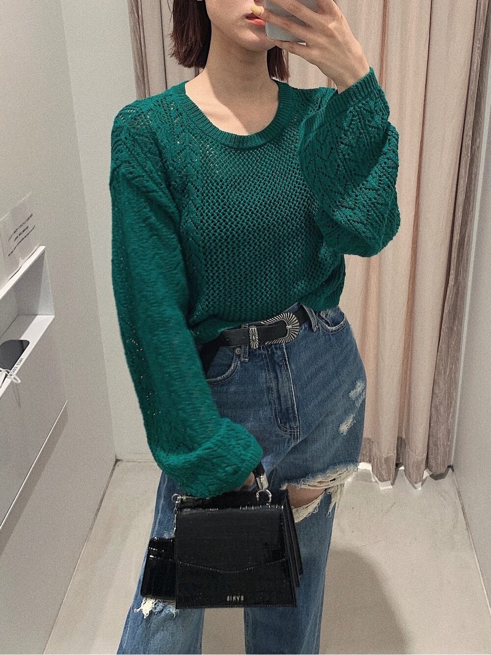 ブラック系のブーツ、ブルー系のデニムパンツ、グリーン系のニット/セーターを着用したレディースの春コーディネートの3枚目の写真