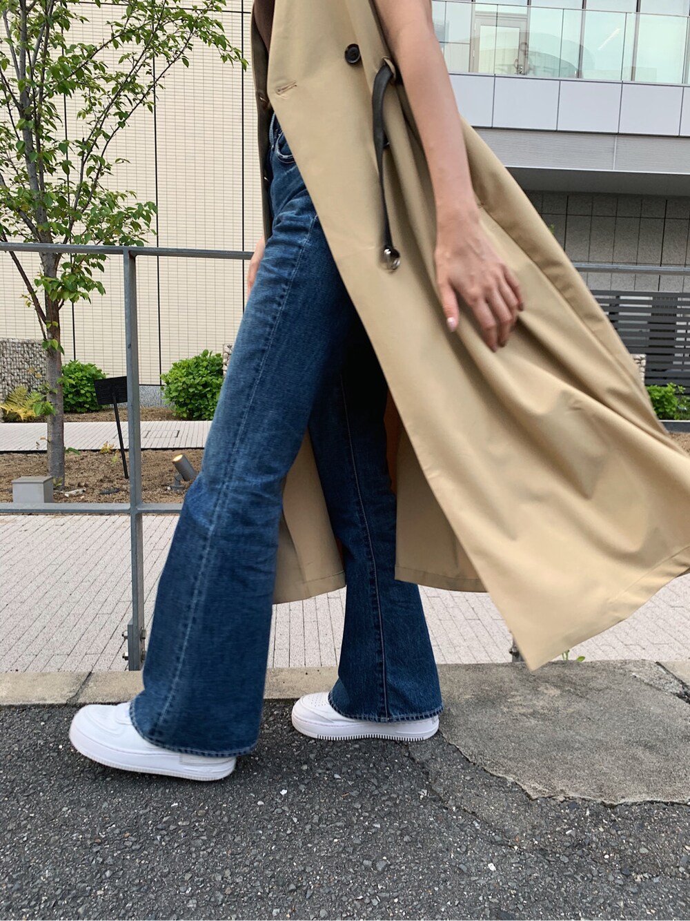ブルー系のデニムパンツ、ベージュ系のトレンチコート、ブラウン系のタンクトップを着用したレディースの春コーディネートの8枚目の写真