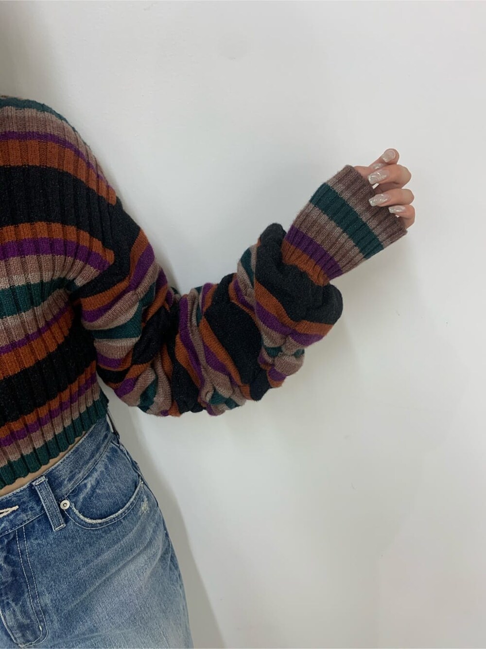 ブラック系のハンドバッグ、ブラック系のブーツ、ブルー系のデニムパンツを着用したレディースの秋コーディネートの6枚目の写真