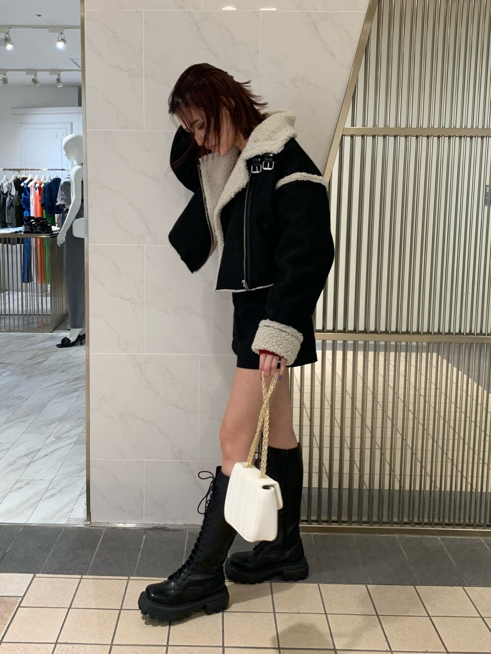 レッド系のニット/セーター、ブラック系のムートンコート、ブラック系のその他パンツを着用したレディースの夏コーディネートの3枚目の写真