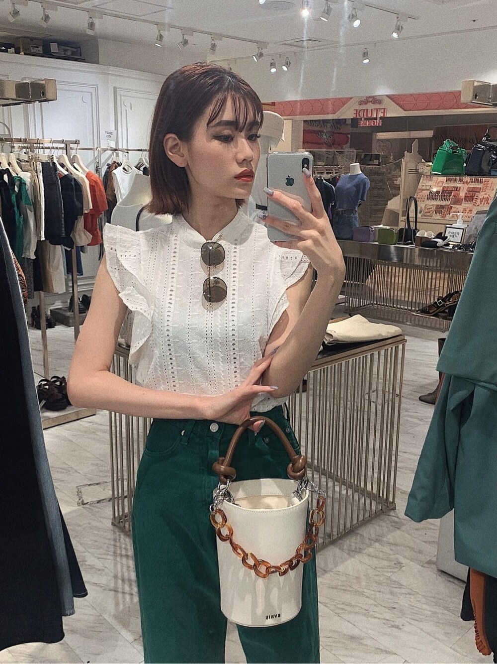 グリーン系のデニムパンツ、ホワイト系のタンクトップ、ホワイト系のサンダルを着用したレディースの春コーディネートの2枚目の写真