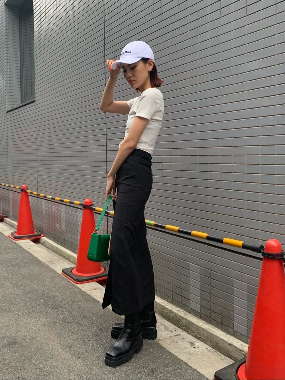 ブラック系のスカート、ブラック系のブーツ、グリーン系のショルダーバッグを着用したレディースの夏コーディネートの2枚目の写真