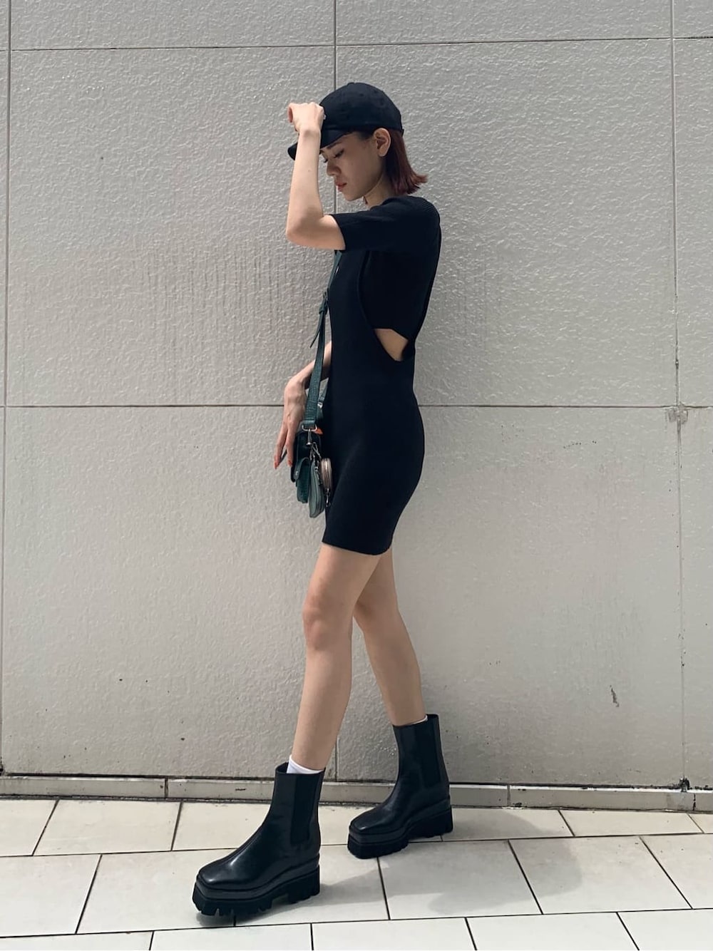 ブラック系のワンピース、ブラック系のブーツ、グリーン系のショルダーバッグを着用したレディースの夏コーディネートの2枚目の写真