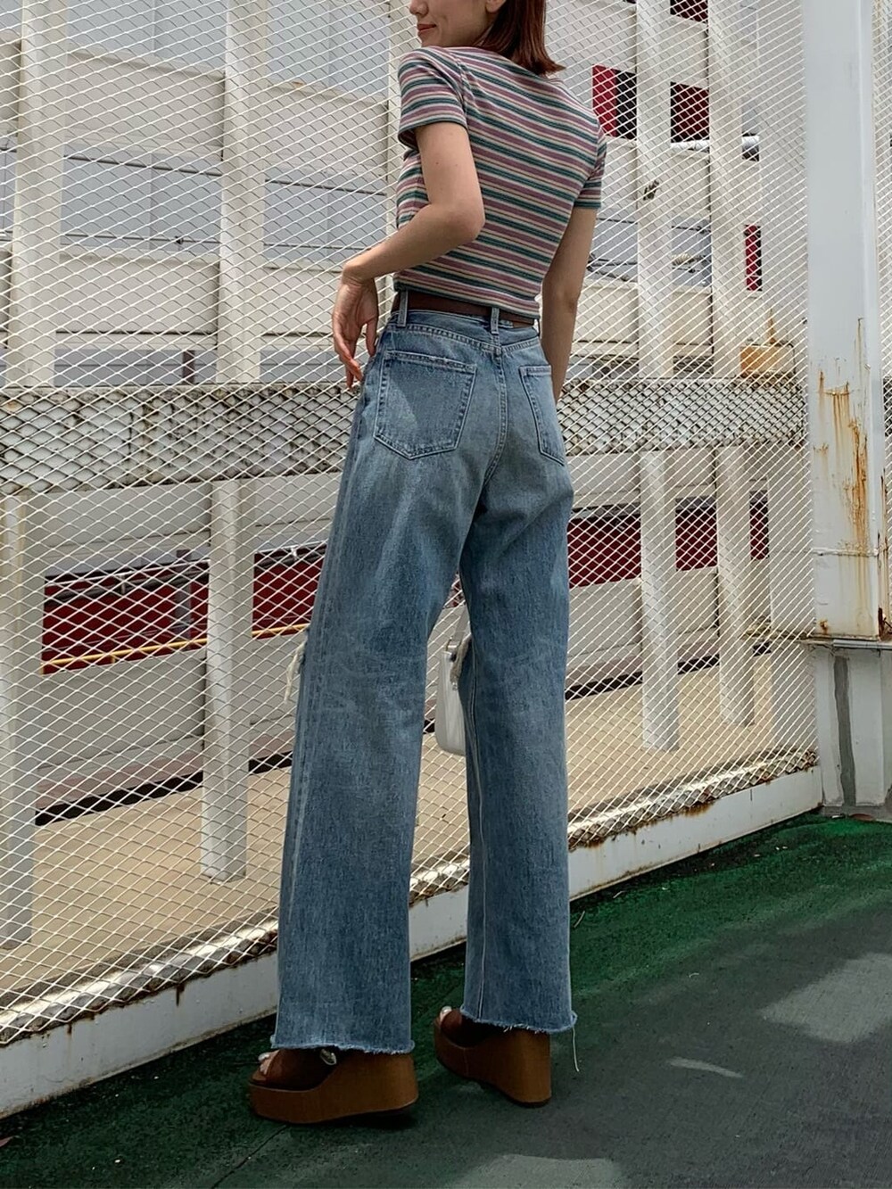 ブラウン系のサンダル、ブルー系のデニムパンツ、ホワイト系のショルダーバッグを着用したレディースの夏コーディネートの2枚目の写真