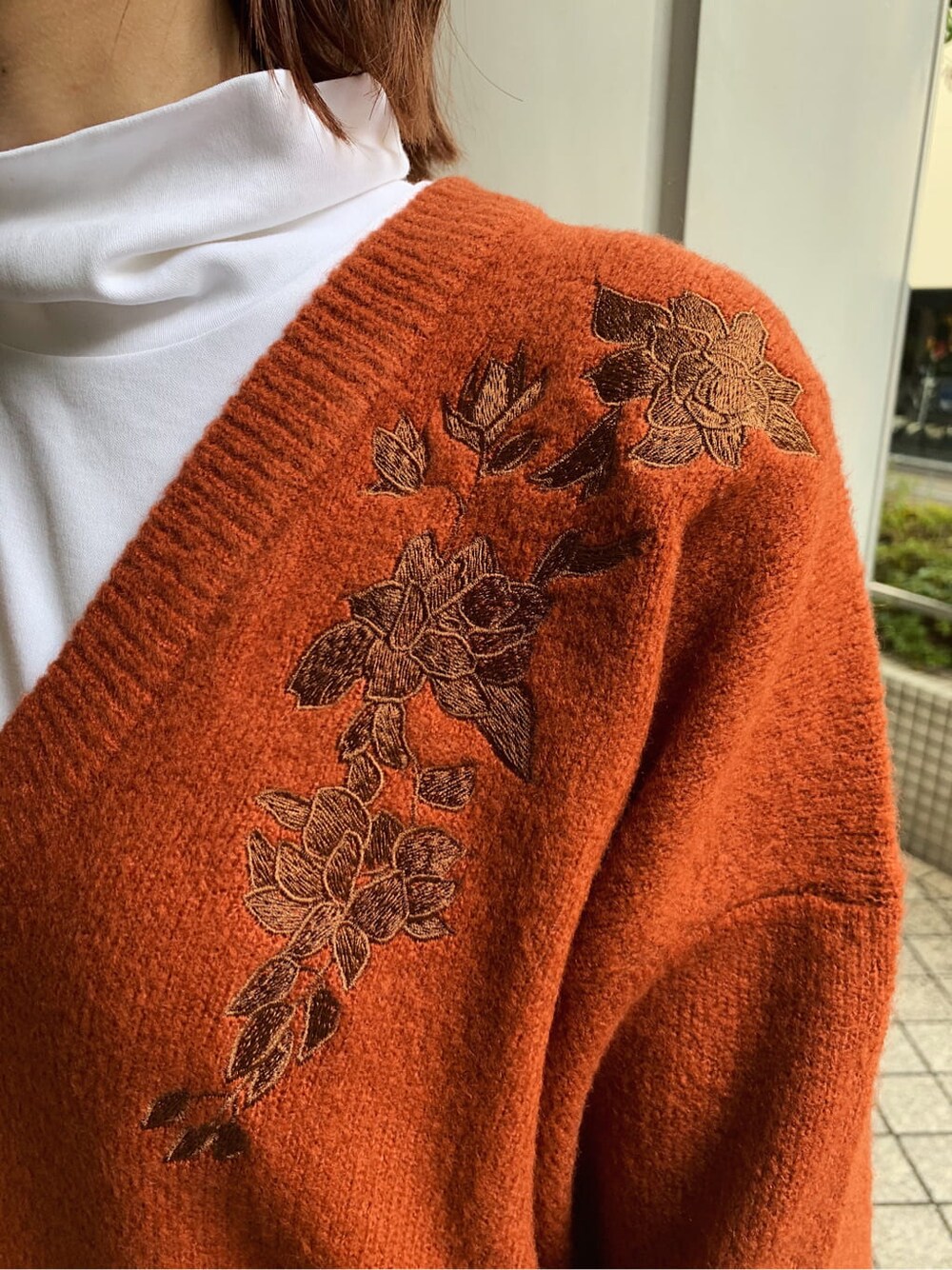 オレンジ系のニット/セーター、ブラック系のブーツ、ブラック系のスカートを着用したレディースの冬コーディネートの4枚目の写真