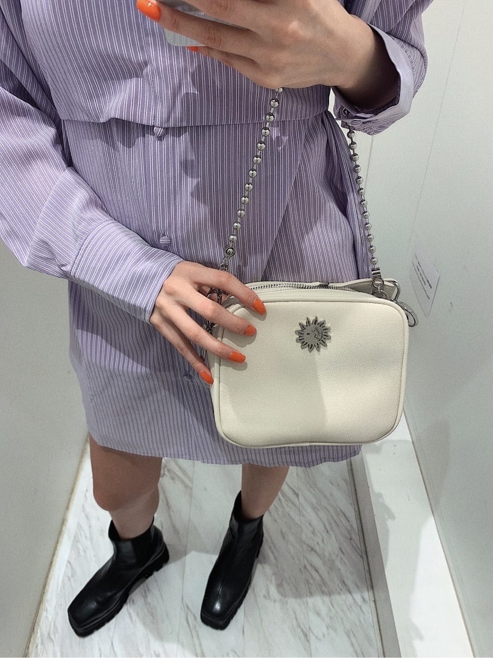 ホワイト系のスカート、ブラック系のブーツ、ホワイト系のショルダーバッグを着用したレディースの春コーディネートの8枚目の写真