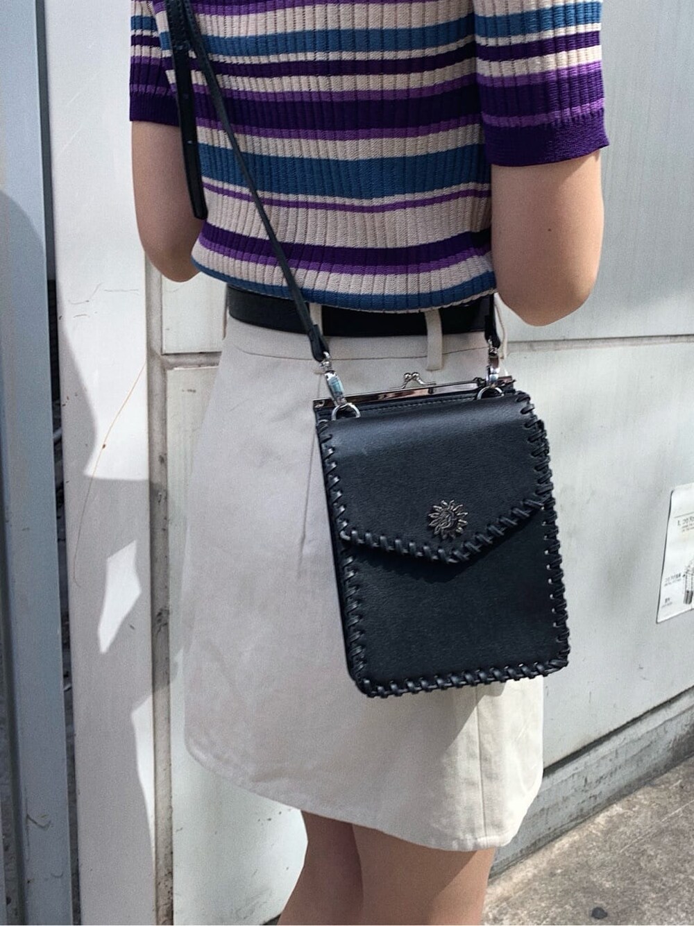 ブラック系のショルダーバッグ、ホワイト系のスカート、パープル系のニット/セーターを着用したレディースの春コーディネートの7枚目の写真