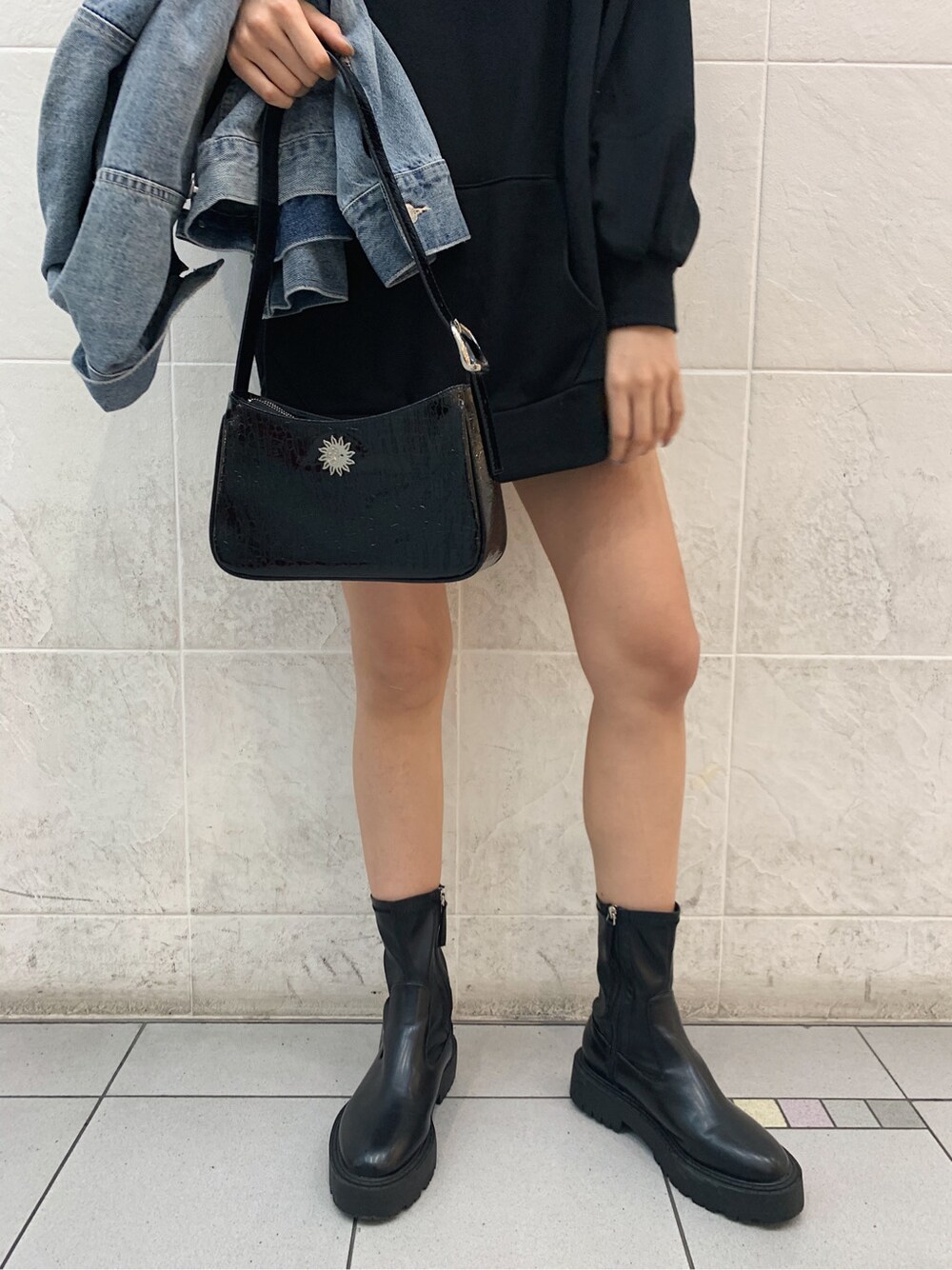 ブルー系のデニムジャケット、ブラック系のスカート、ブラック系のショルダーバッグを着用したレディースの春コーディネートの2枚目の写真