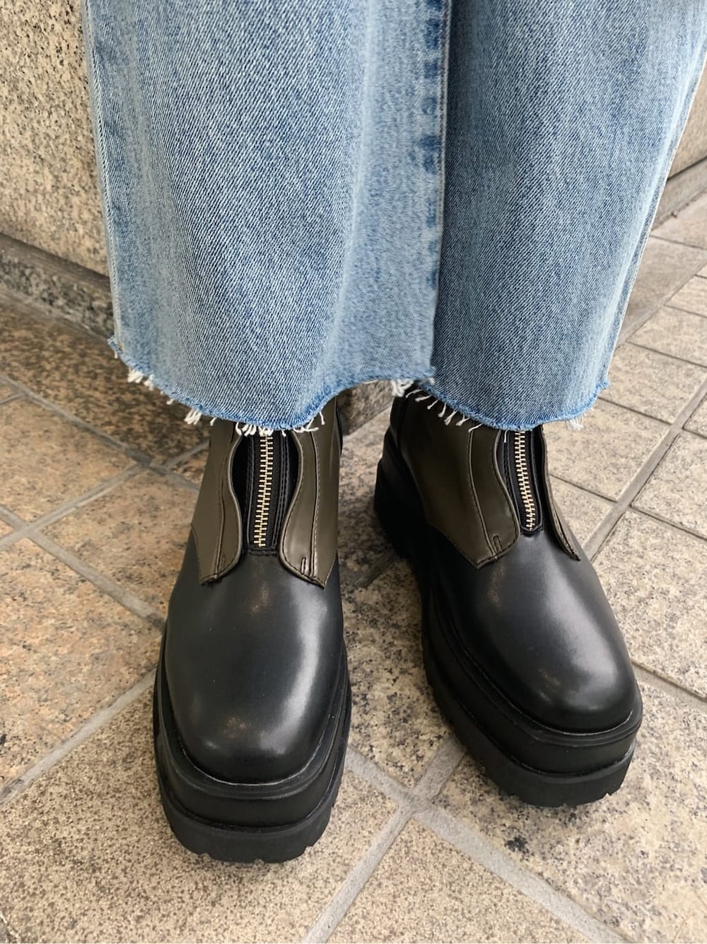 ホワイト系のニット/セーター、ベージュ系のブーツ、ブラック系のトレンチコートを着用したレディースの冬コーディネートの9枚目の写真