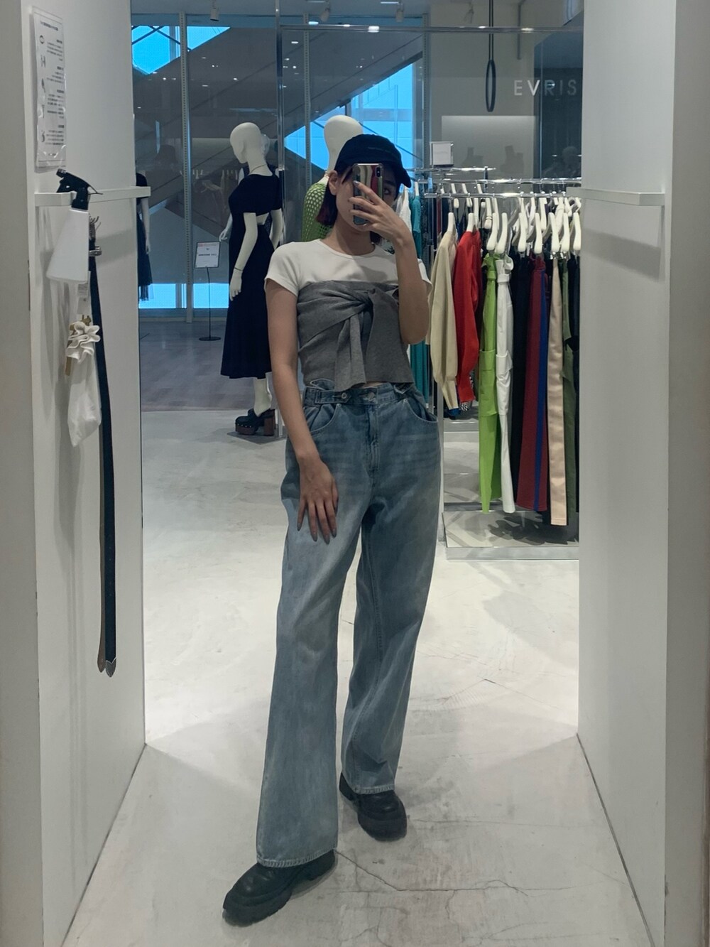 ブルー系のデニムパンツ、ブラック系のブーツ、グレー系のチューブトップを着用したレディースの春コーディネートの2枚目の写真