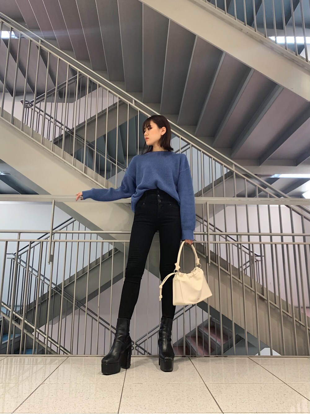 ブラック系のデニムパンツ、ホワイト系のショルダーバッグ、ブルー系のニット/セーターを着用したレディースの冬コーディネートの4枚目の写真