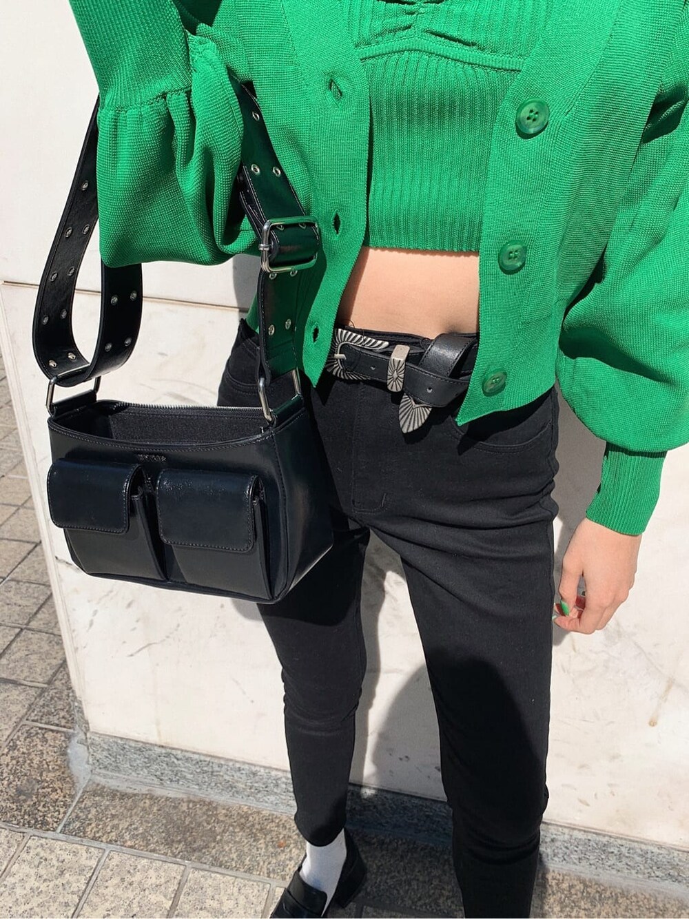 ブラック系のデニムパンツ、ブラック系のローファー、ブラック系のショルダーバッグを着用したレディースの春コーディネートの6枚目の写真