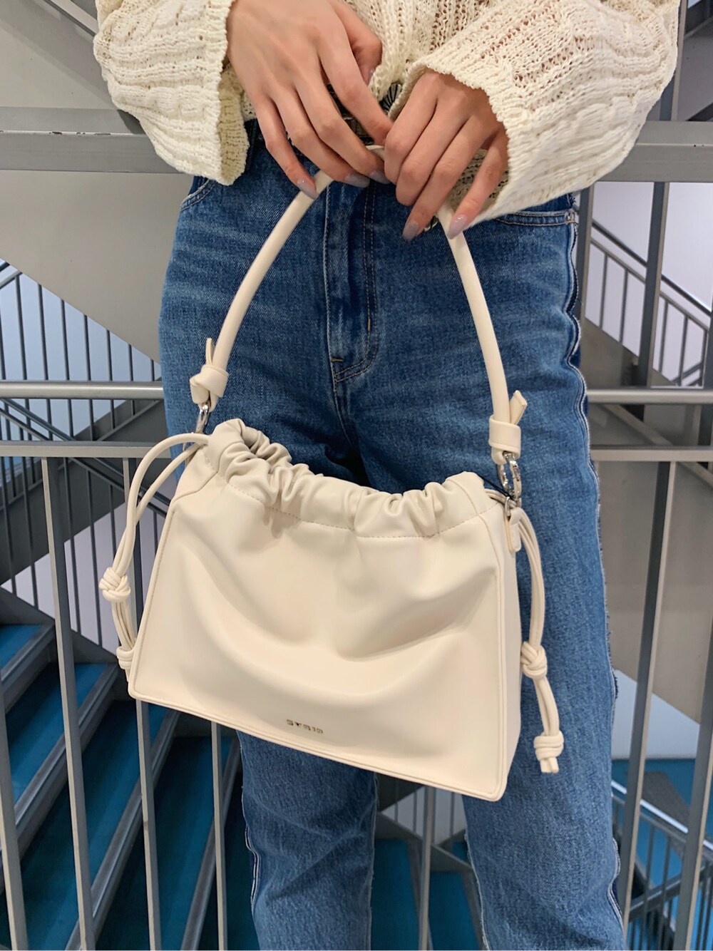 ホワイト系のニット/セーター、ベージュ系のパンプス、ホワイト系のショルダーバッグを着用したレディースの春コーディネートの8枚目の写真