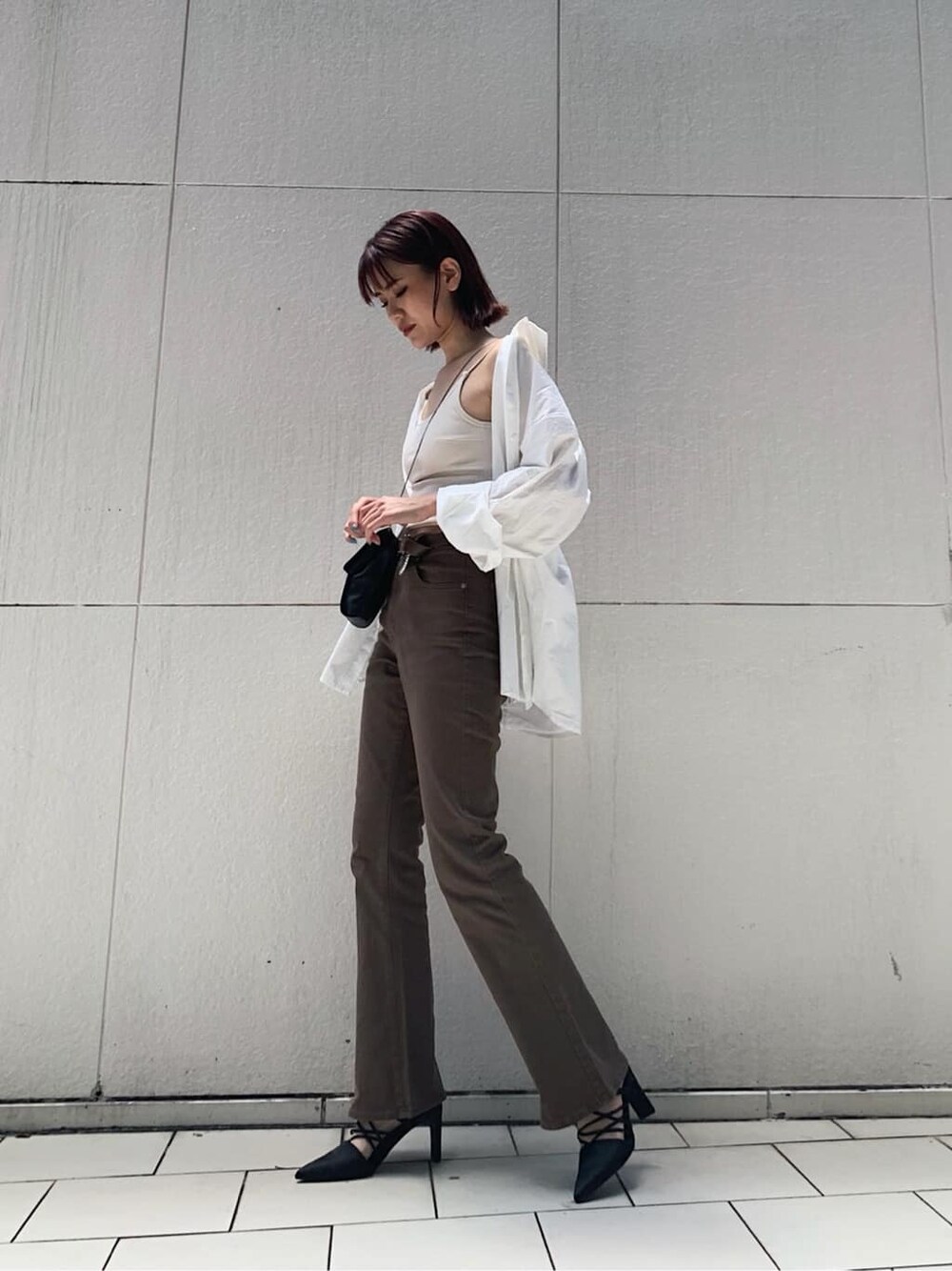 ブラウン系のデニムパンツ、ホワイト系のキャミソール、ブラック系のサンダルを着用したレディースの秋コーディネートの2枚目の写真