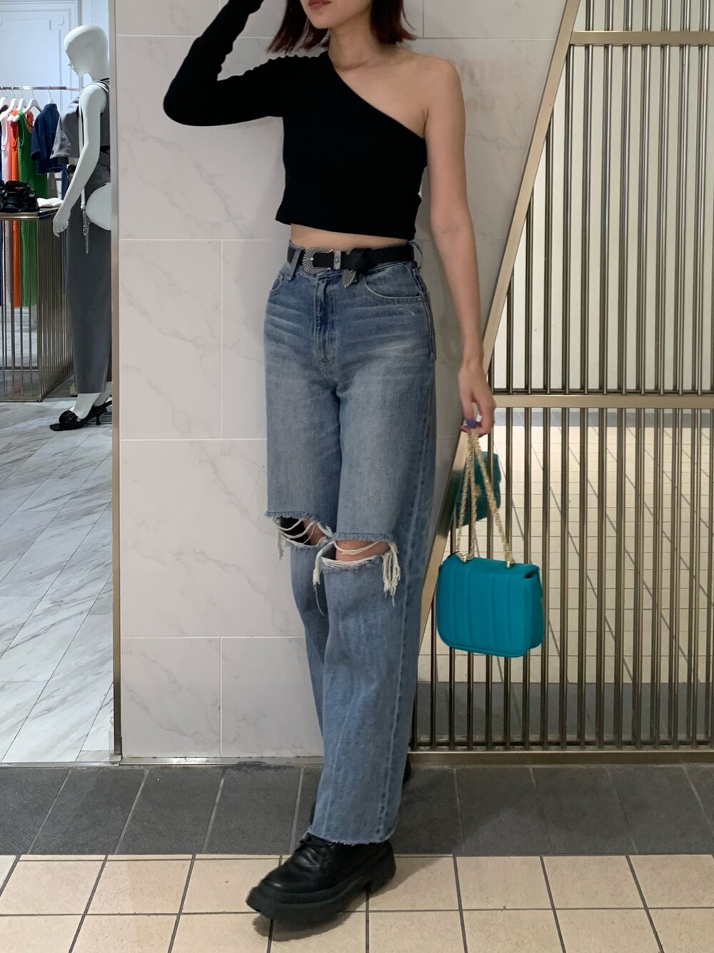 ブラック系のブーツ、ブルー系のデニムパンツ、ブルー系のショルダーバッグを着用したレディースの夏コーディネートの2枚目の写真