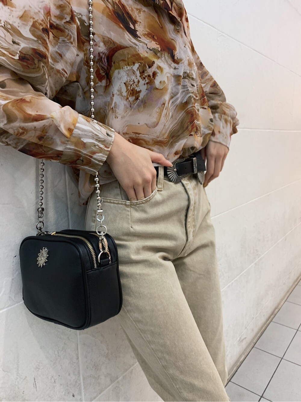 ブラウン系のキャミソール、ブラック系のサンダル、ベージュ系のデニムパンツを着用したレディースの春コーディネートの4枚目の写真