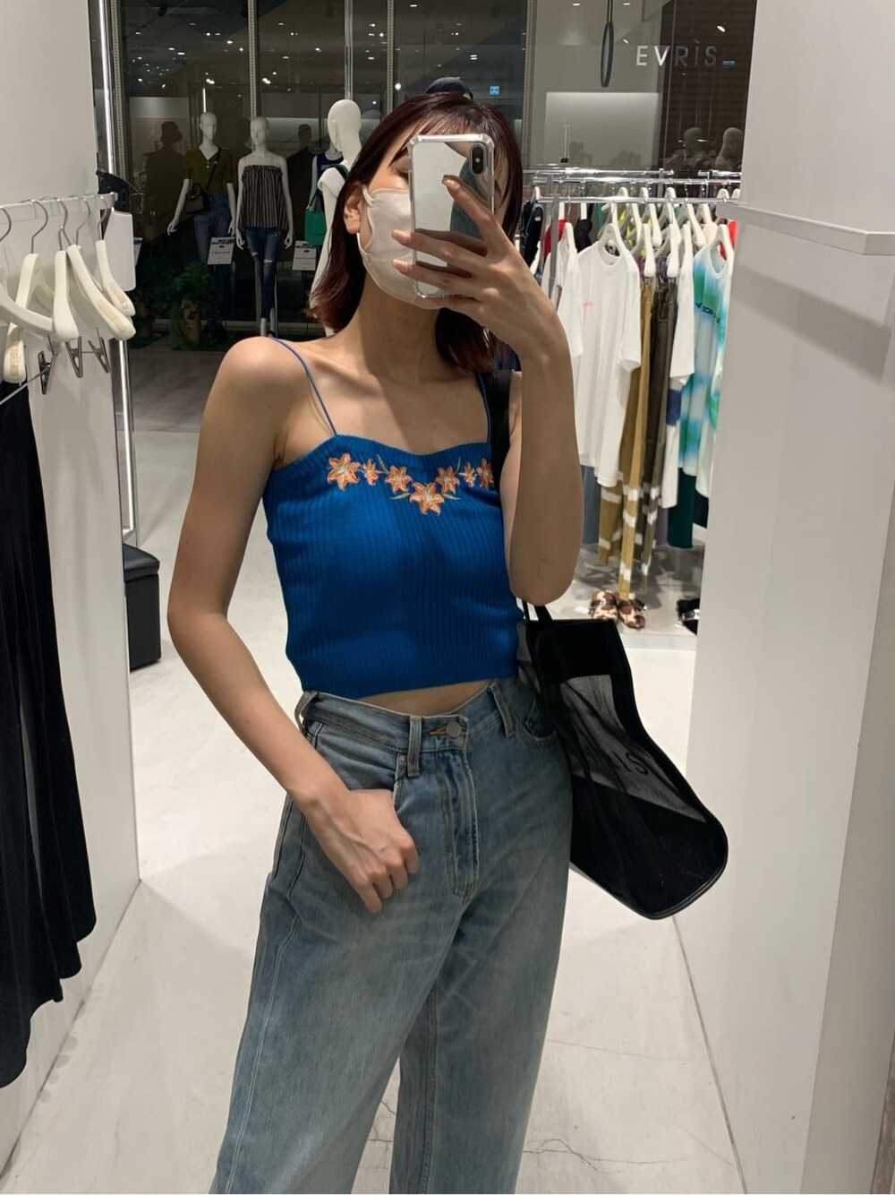 ブラック系のサンダル、ブルー系のデニムパンツ、ブラック系のトートバッグを着用したレディースの夏コーディネートの2枚目の写真