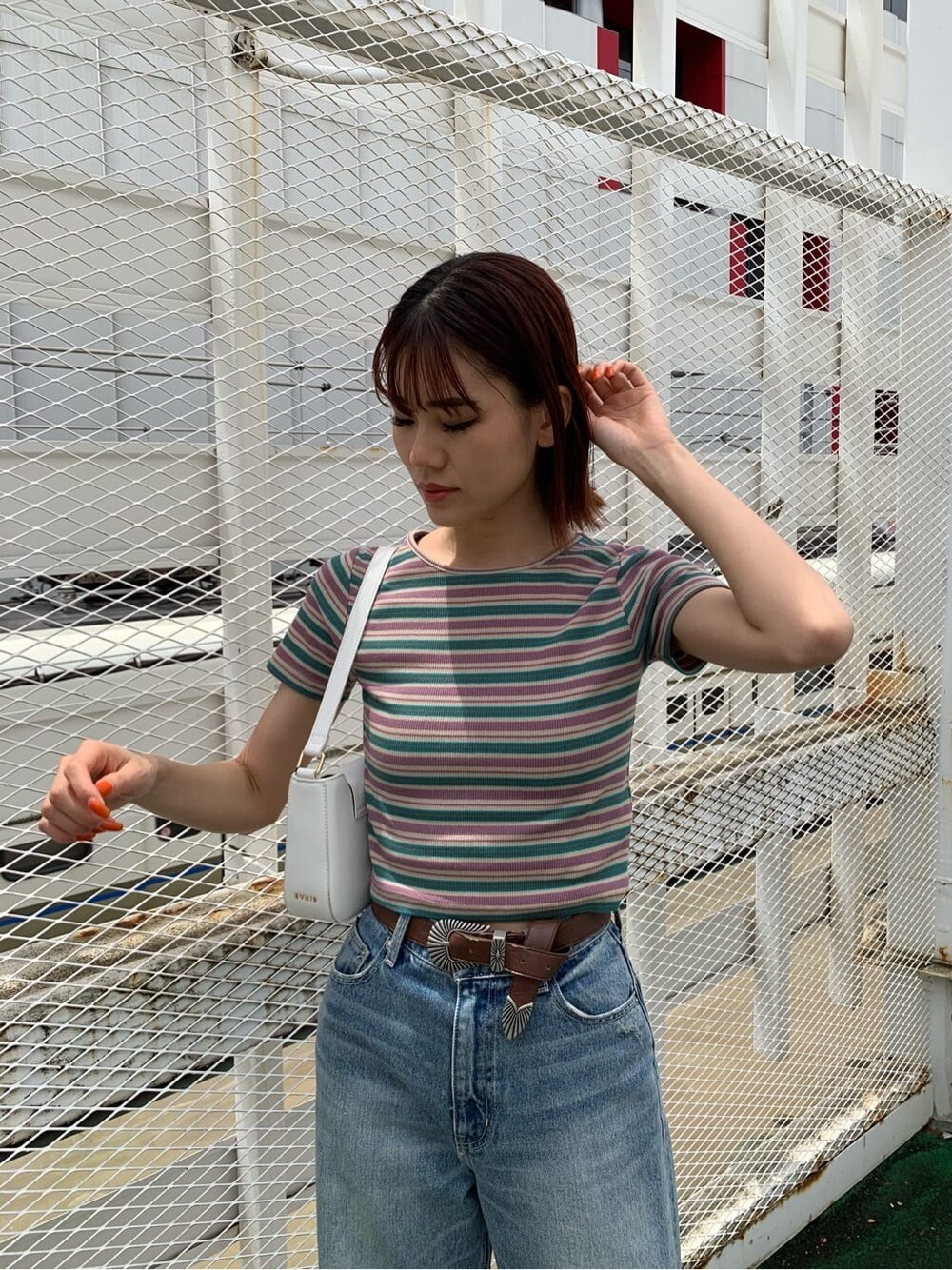 ブラウン系のサンダル、ブルー系のデニムパンツ、ホワイト系のショルダーバッグを着用したレディースの夏コーディネートの3枚目の写真