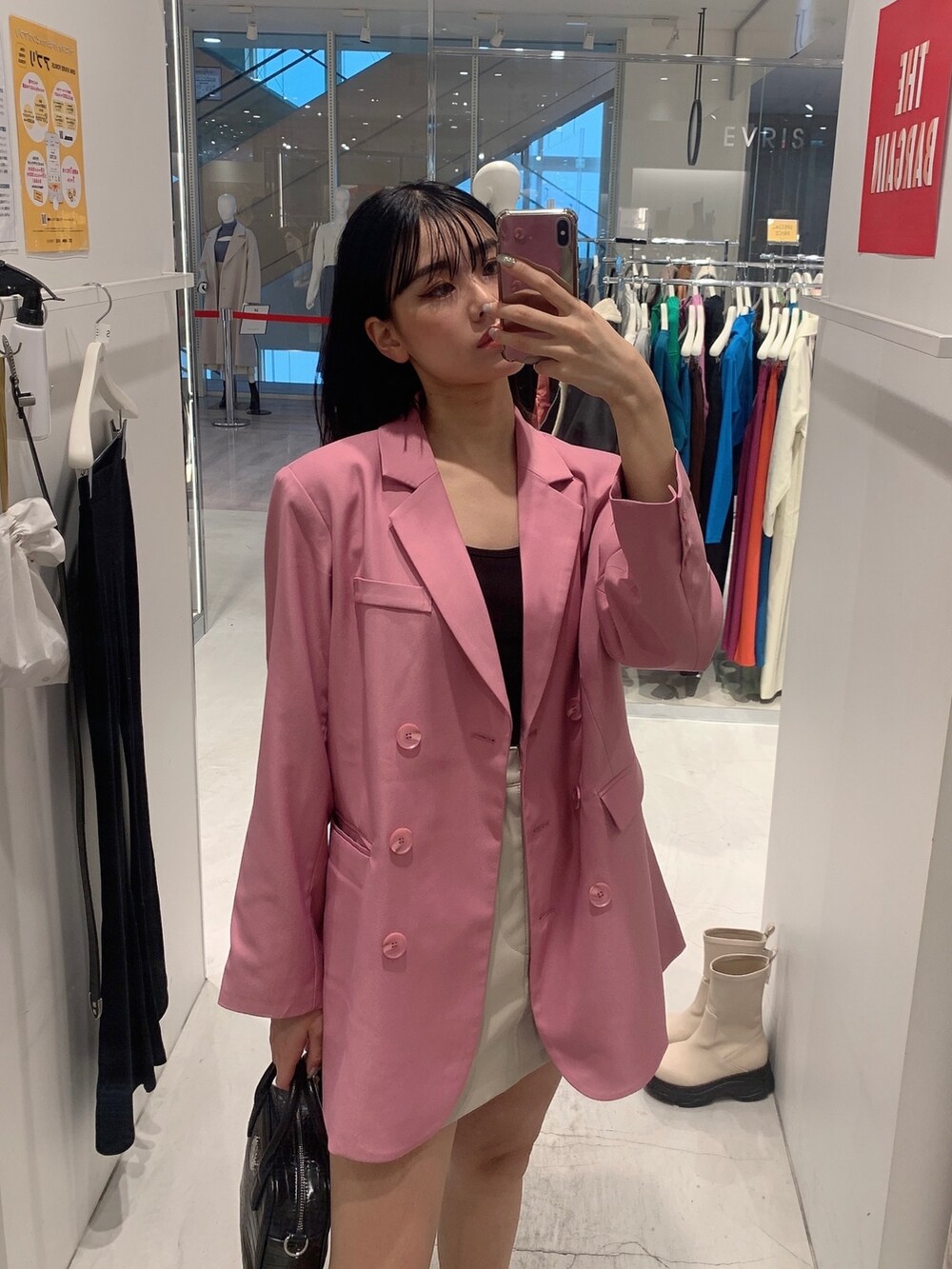 ピンク系のテーラードジャケット、ホワイト系のスカート、ブラック系のショルダーバッグを着用したレディースの冬コーディネートの2枚目の写真