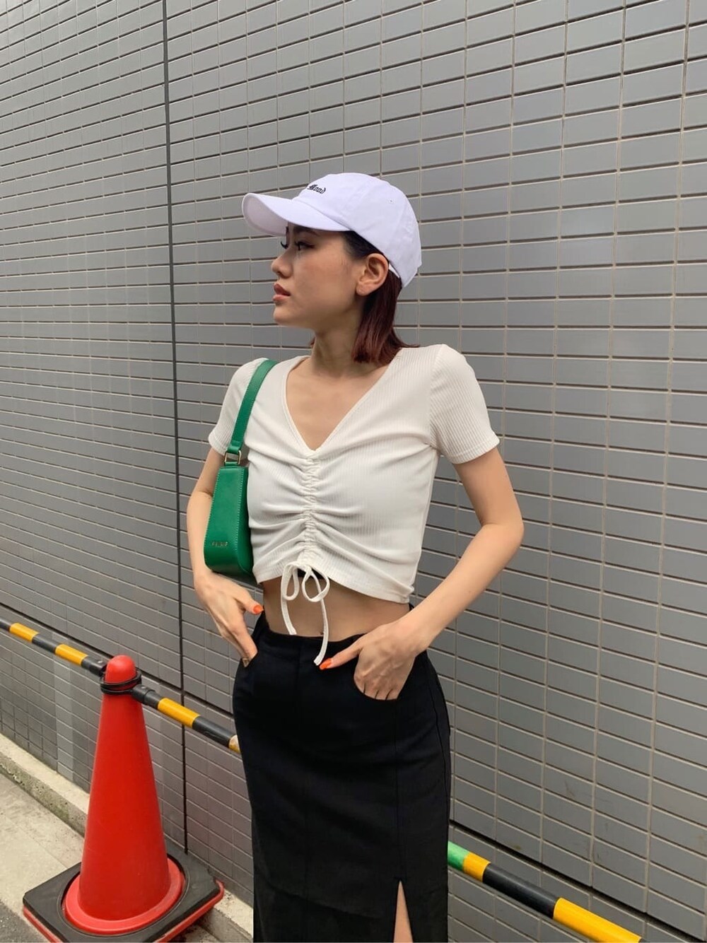 ブラック系のスカート、ブラック系のブーツ、グリーン系のショルダーバッグを着用したレディースの夏コーディネートの4枚目の写真