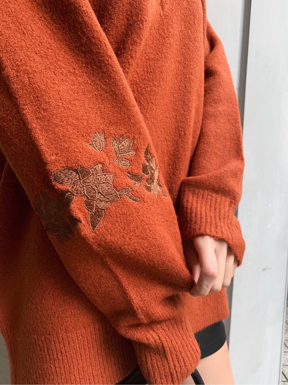 オレンジ系のニット/セーター、ブラック系のブーツ、ブラック系のスカートを着用したレディースの冬コーディネートの5枚目の写真