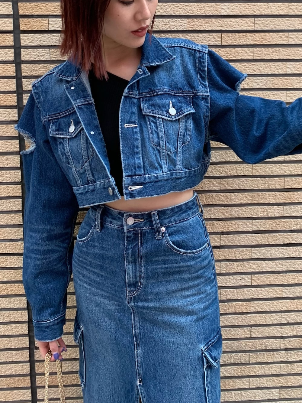 ブルー系のデニムジャケット、ブルー系のデニムスカート、レッド系のショルダーバッグを着用したレディースの秋コーディネートの4枚目の写真