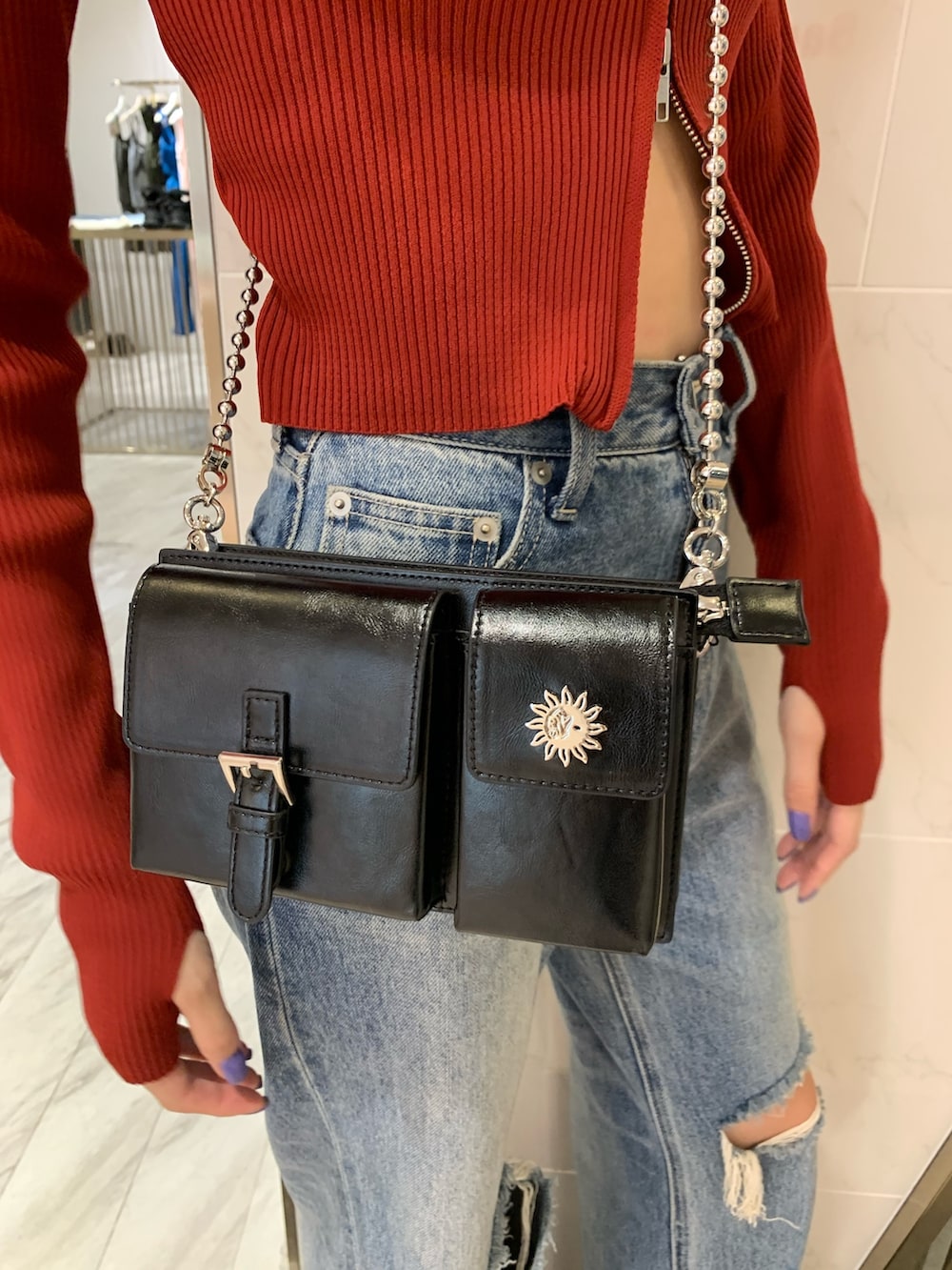 レッド系のニット/セーター、ブラック系のショルダーバッグ、ブルー系のデニムパンツを着用したレディースの夏コーディネートの6枚目の写真