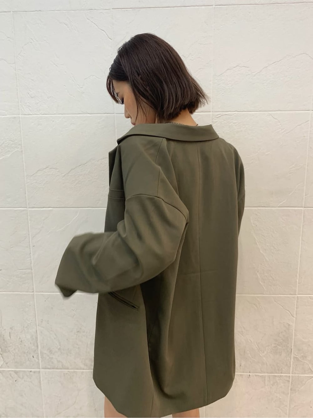 ホワイト系のキャミソール、ベージュ系のテーラードジャケット、ブラック系のブーツを着用したレディースの秋コーディネートの3枚目の写真