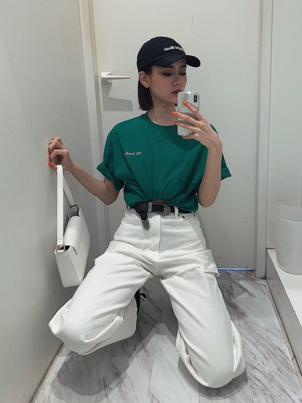 ブラック系のスニーカー、ホワイト系のショルダーバッグ、ホワイト系のデニムパンツを着用したレディースの春コーディネートの6枚目の写真