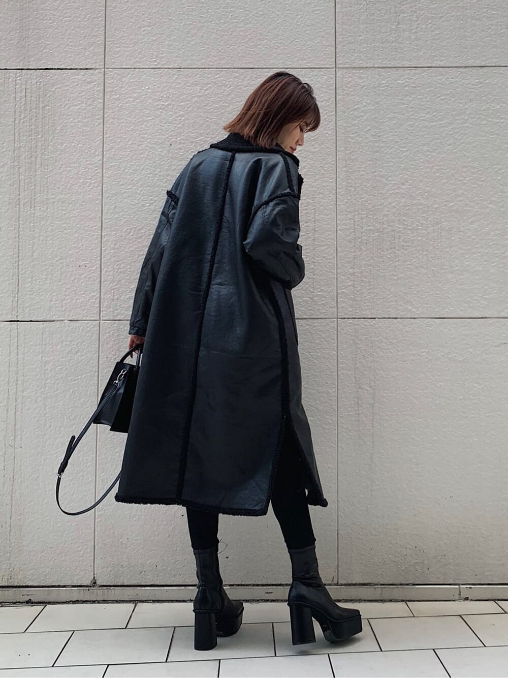 ブラック系のデニムパンツ、ブラック系のショルダーバッグ、ブラック系のブーツを着用したレディースの冬コーディネートの2枚目の写真