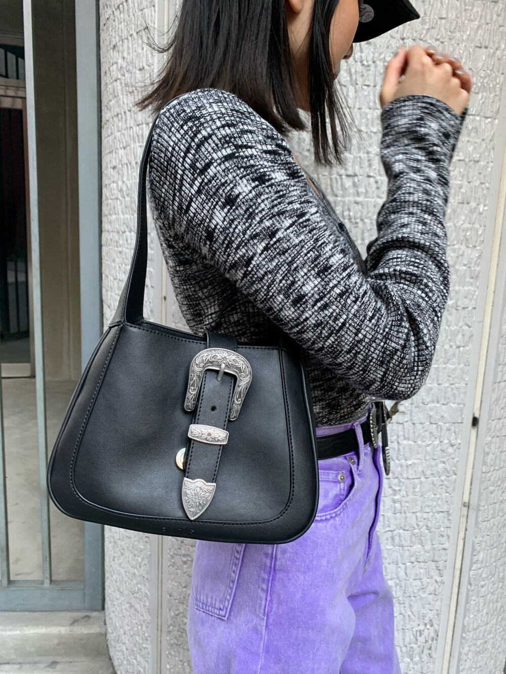 パープル系のデニムパンツ、ブラック系のニット/セーター、ブラック系のハンドバッグを着用したレディースの冬コーディネートの6枚目の写真