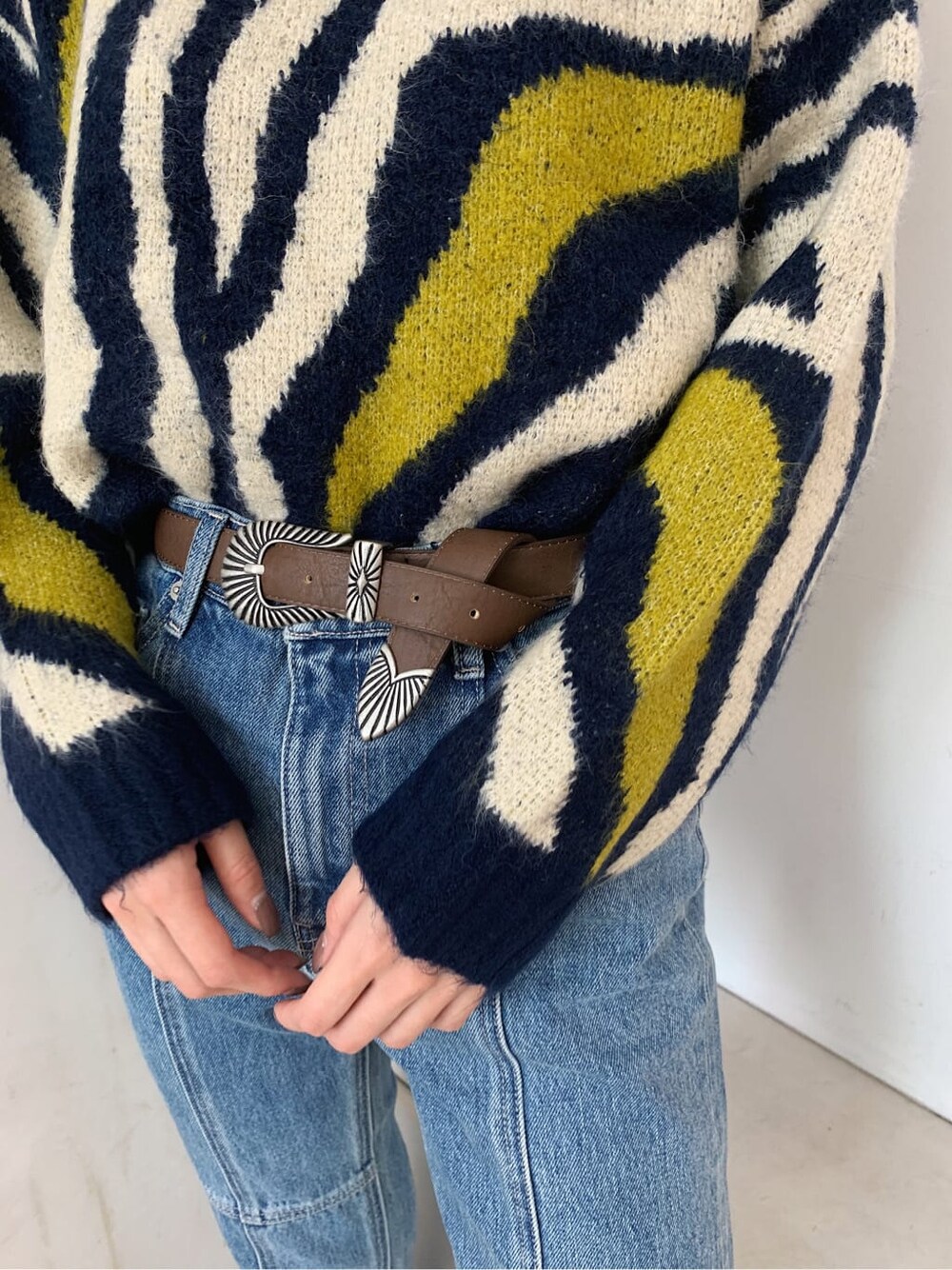 ブルー系のデニムパンツ、ブラウン系のベルトを着用したレディースの秋コーディネートの5枚目の写真